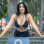 Smiling woman in a park bench at Ciudad de México, showcasing casual fashion.